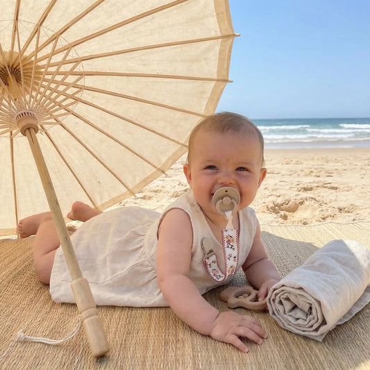 bébé à la plage avec attache tetine bebe