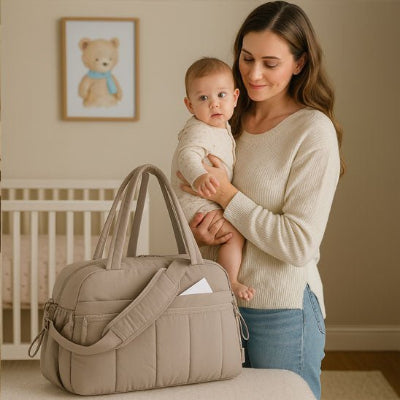bebe bras maman regardant sac a langer camel